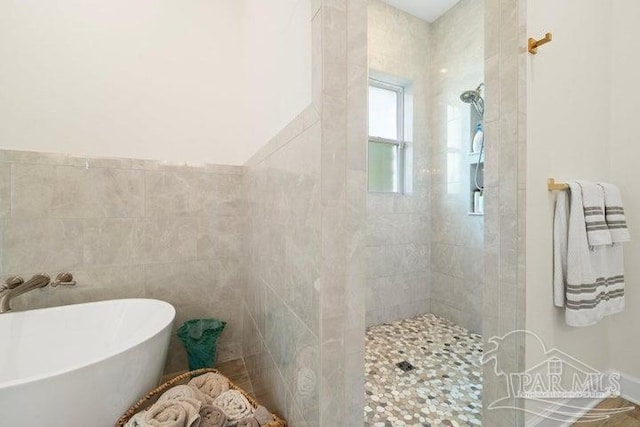 bathroom featuring sink, independent shower and bath, and tile walls