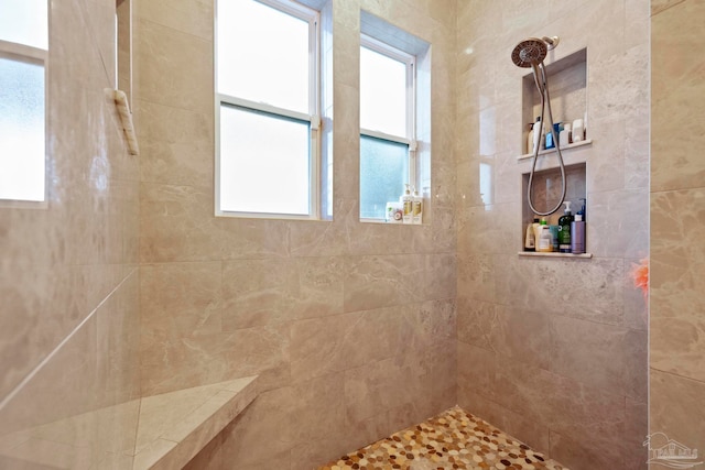 bathroom featuring plenty of natural light and tiled shower