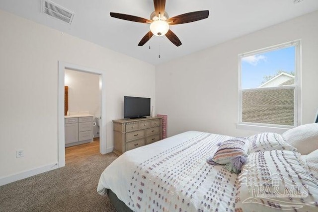 carpeted bedroom with ensuite bathroom and ceiling fan