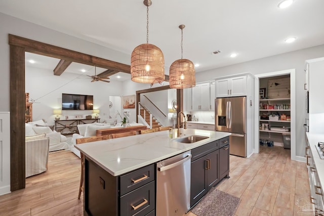 kitchen featuring hanging light fixtures, sink, an island with sink, appliances with stainless steel finishes, and white cabinetry