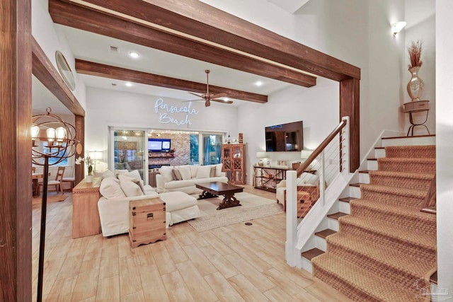 living room featuring beamed ceiling, ceiling fan with notable chandelier, a towering ceiling, and light hardwood / wood-style flooring