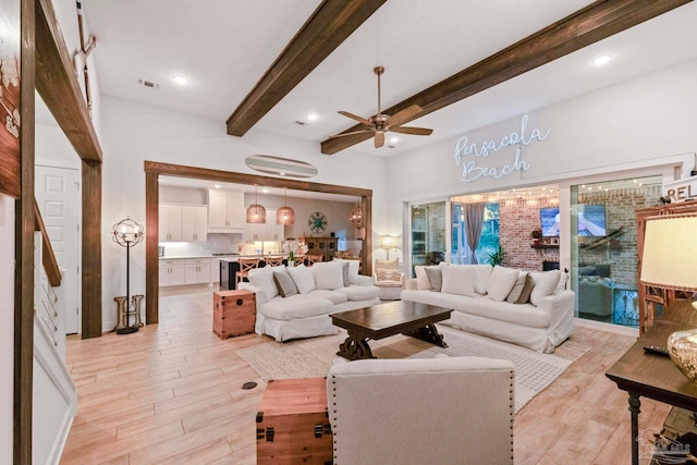 living room with ceiling fan, light hardwood / wood-style flooring, and beamed ceiling