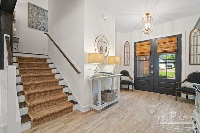 foyer featuring a notable chandelier, light wood-type flooring, and french doors