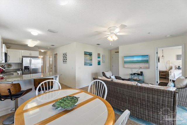 dining space featuring a textured ceiling and ceiling fan