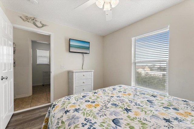 bedroom with dark wood-type flooring, a textured ceiling, and ceiling fan