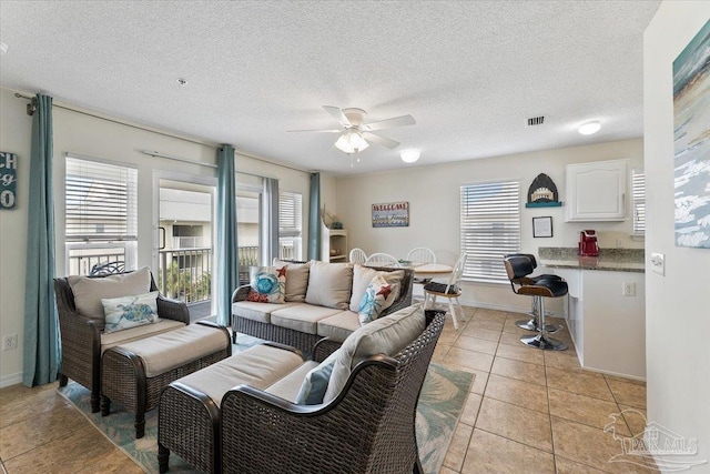 tiled living room with ceiling fan and a textured ceiling