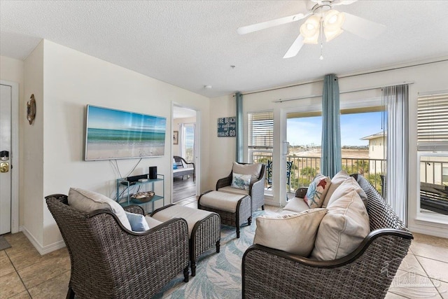 living room with light tile patterned flooring, ceiling fan, and a textured ceiling