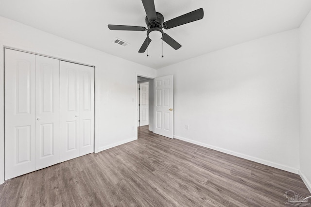 unfurnished bedroom featuring ceiling fan, a closet, and wood-type flooring