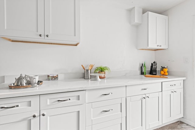 bar featuring white cabinets and light stone countertops