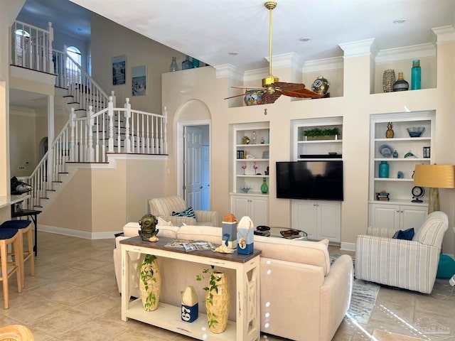 living room with crown molding, ceiling fan, a high ceiling, and built in shelves