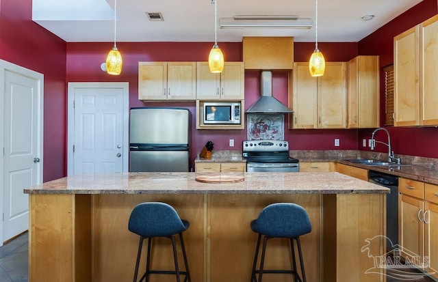 kitchen with pendant lighting, a center island, wall chimney range hood, sink, and stainless steel appliances