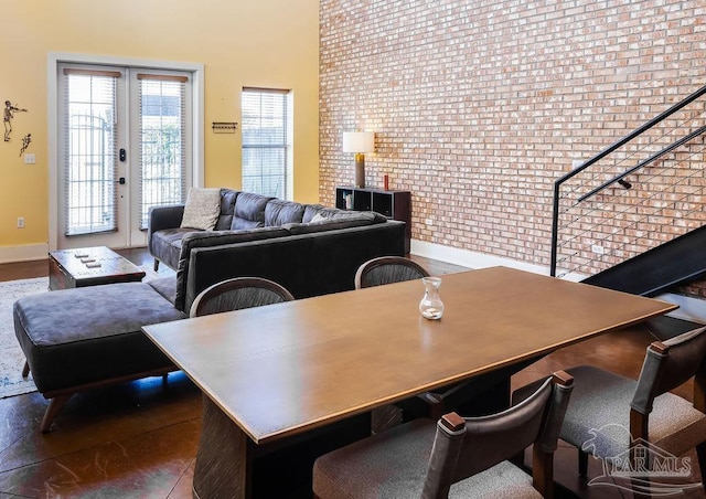 dining area with dark hardwood / wood-style flooring, brick wall, and french doors