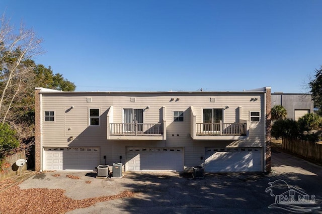 view of front of home with a garage, a balcony, and cooling unit