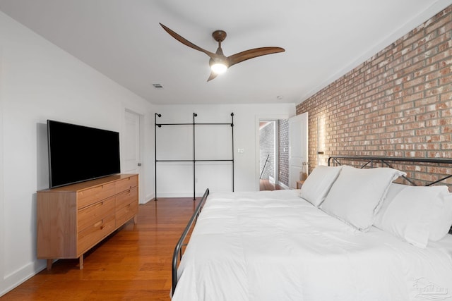 bedroom with ceiling fan, dark wood-type flooring, and brick wall