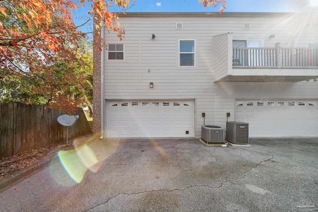 rear view of house with cooling unit, a garage, and a balcony