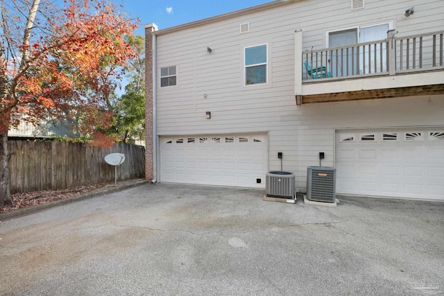 back of property with central AC, a balcony, and a garage