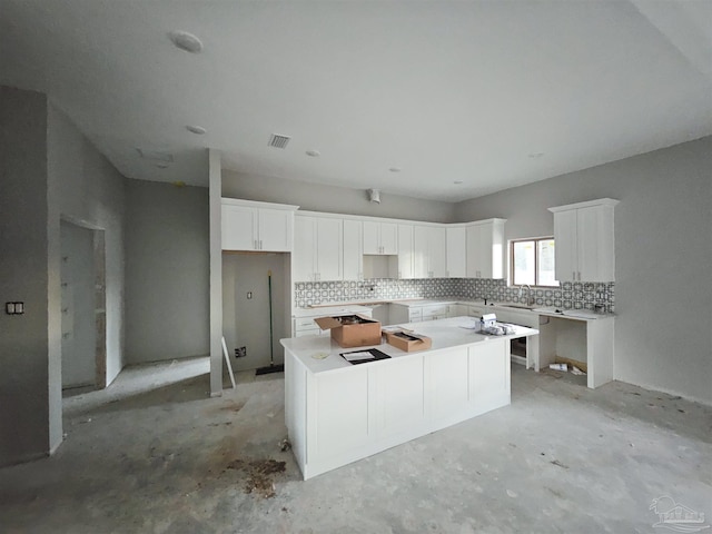 kitchen featuring white cabinets, decorative backsplash, a center island, and sink