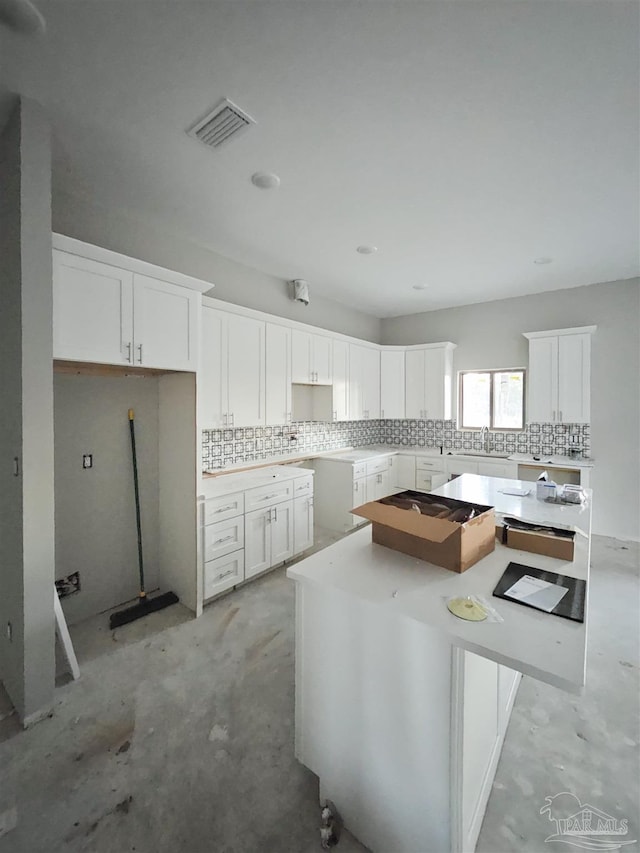 kitchen with white cabinets, a center island, and sink