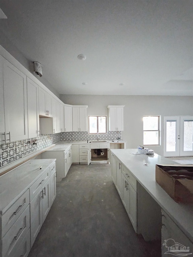 kitchen with decorative backsplash, white cabinetry, and sink