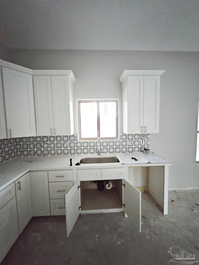 kitchen with light stone countertops, decorative backsplash, white cabinetry, and sink