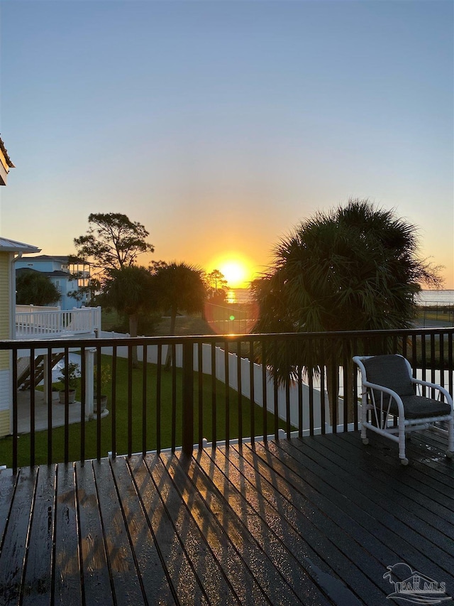 deck at dusk featuring a yard