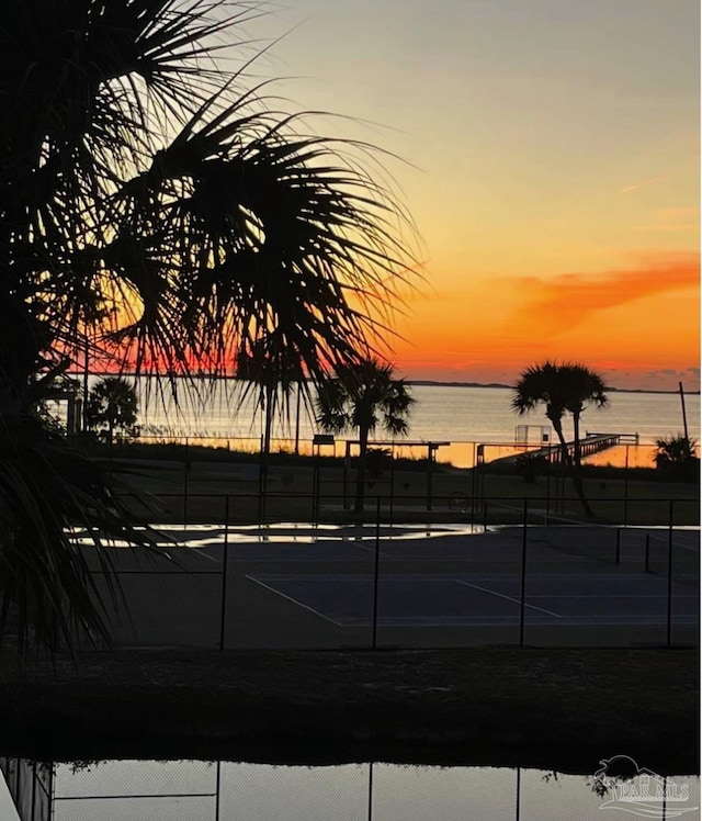 view of sport court featuring a water view and fence