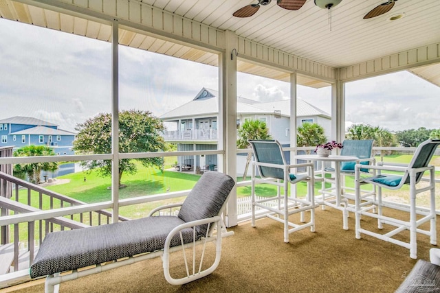 sunroom / solarium with ceiling fan and a residential view