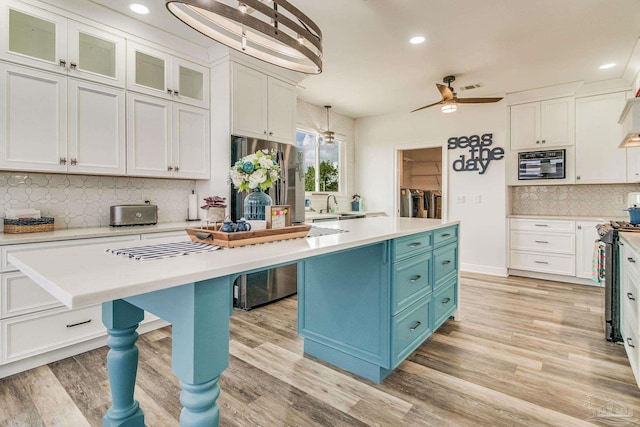 kitchen featuring blue cabinets, a kitchen island, white cabinetry, and stainless steel appliances