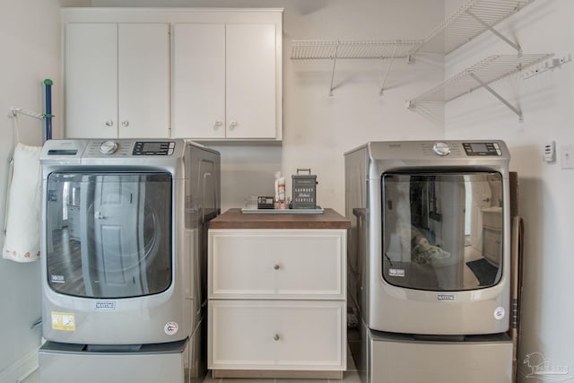 laundry area with washing machine and clothes dryer and cabinets