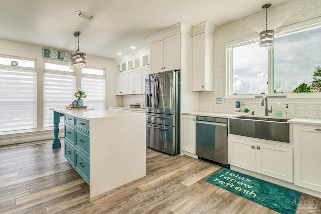 kitchen with light countertops, appliances with stainless steel finishes, a sink, and white cabinets