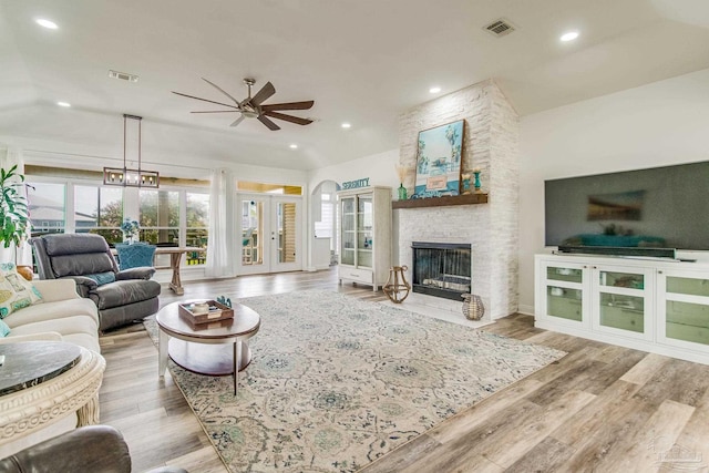 living room featuring visible vents, a stone fireplace, and wood finished floors