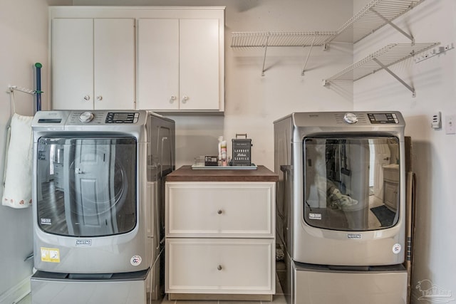 clothes washing area featuring cabinet space and separate washer and dryer