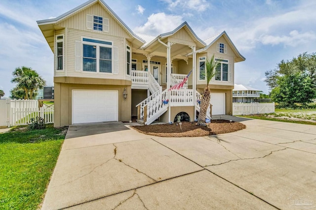 view of front of house with covered porch, a garage, fence, concrete driveway, and stairway