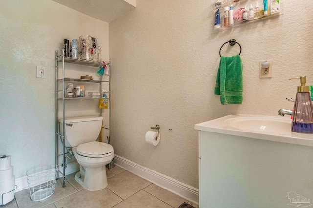 bathroom featuring toilet, vanity, baseboards, and tile patterned floors