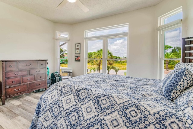 bedroom with ceiling fan, light wood-style flooring, and a textured ceiling