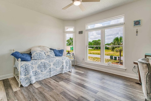 sitting room with a textured ceiling, ceiling fan, wood finished floors, and baseboards