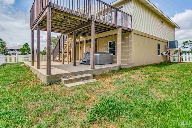 back of property featuring a fenced backyard, stairs, a yard, a patio area, and a hot tub