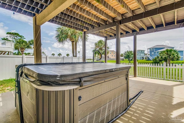 view of patio with a hot tub and fence