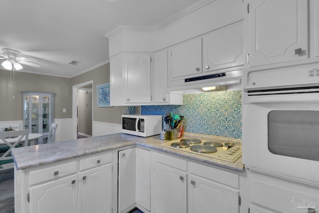 kitchen with white appliances, crown molding, kitchen peninsula, ceiling fan, and white cabinetry