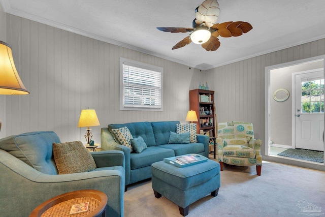 living room with crown molding, wooden walls, carpet floors, and ceiling fan