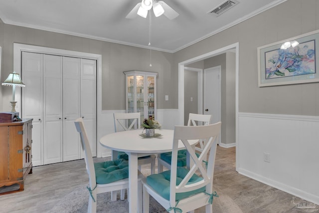 dining space with ceiling fan, light wood-type flooring, and crown molding