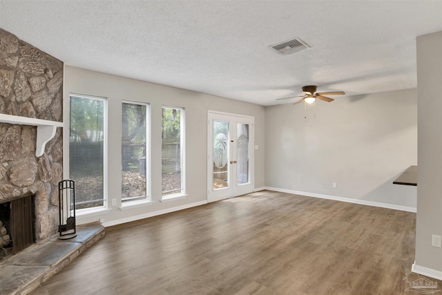 unfurnished living room featuring a textured ceiling, a fireplace, wood finished floors, and visible vents