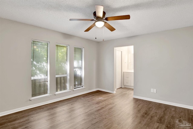 unfurnished room with ceiling fan, a textured ceiling, baseboards, and wood finished floors