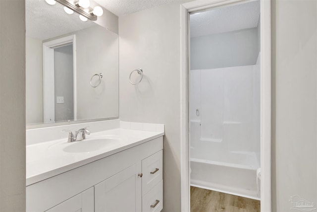 full bath featuring tub / shower combination, a textured ceiling, vanity, and wood finished floors