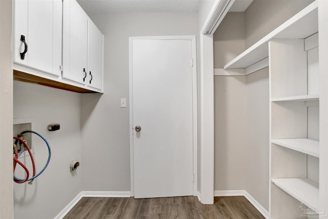 washroom with cabinet space, hookup for a washing machine, baseboards, and wood finished floors