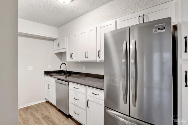 kitchen featuring stainless steel appliances, light wood-type flooring, white cabinets, and a sink