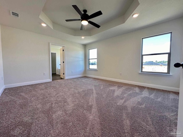 spare room with ceiling fan, a tray ceiling, and carpet flooring