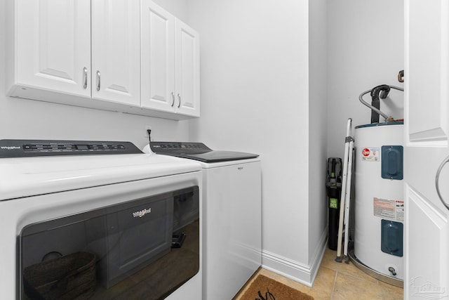 clothes washing area featuring electric water heater, washing machine and dryer, cabinets, and light tile patterned floors