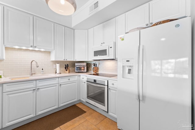 kitchen featuring decorative backsplash, white cabinetry, white appliances, and light tile patterned floors