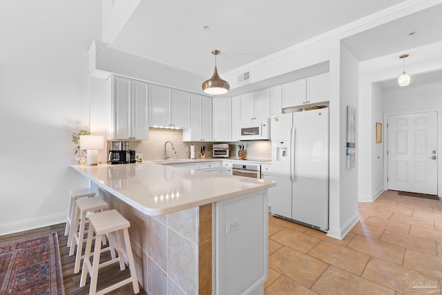 kitchen with white cabinetry, white appliances, light tile patterned floors, kitchen peninsula, and decorative backsplash